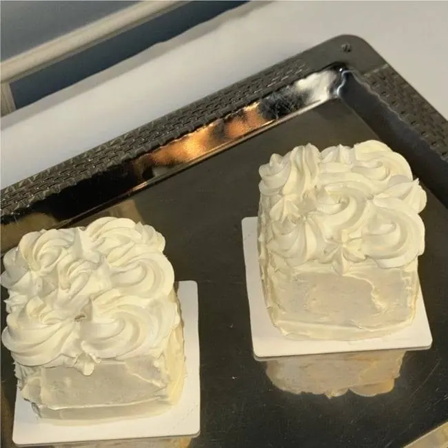 Two cream cakes on a dark tray