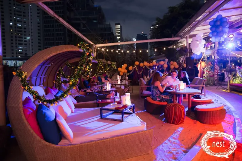 Guests relaxing in Nest's rooftop cabanas at night